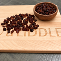 Black raisins on the engraved board with the brown bowl added in the upper right corner
