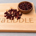 Dried cranberries on the engraved board with the brown bowl added in the upper right corner