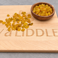 Golden raisins on the engraved board with the brown bowl added in the upper right corner